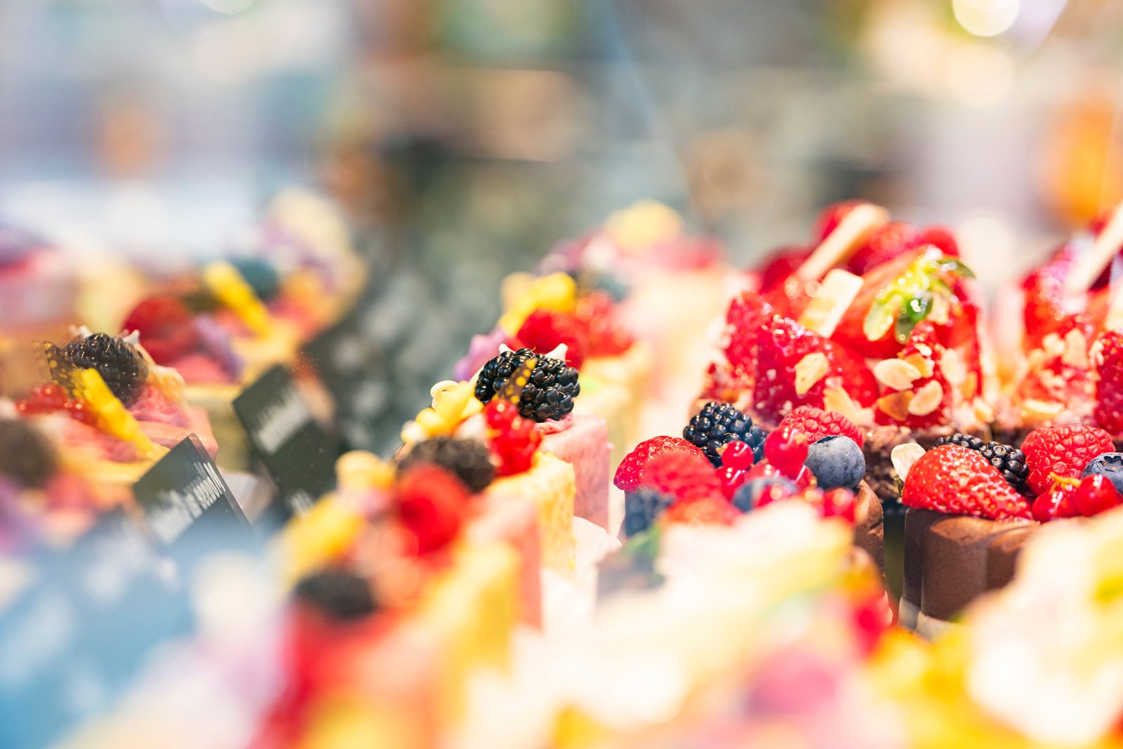 Bunte Petit Fours mit frischen Beeren in der Vitrine — Brotzeit Rostock